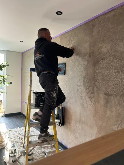 man on ladder painting a wall